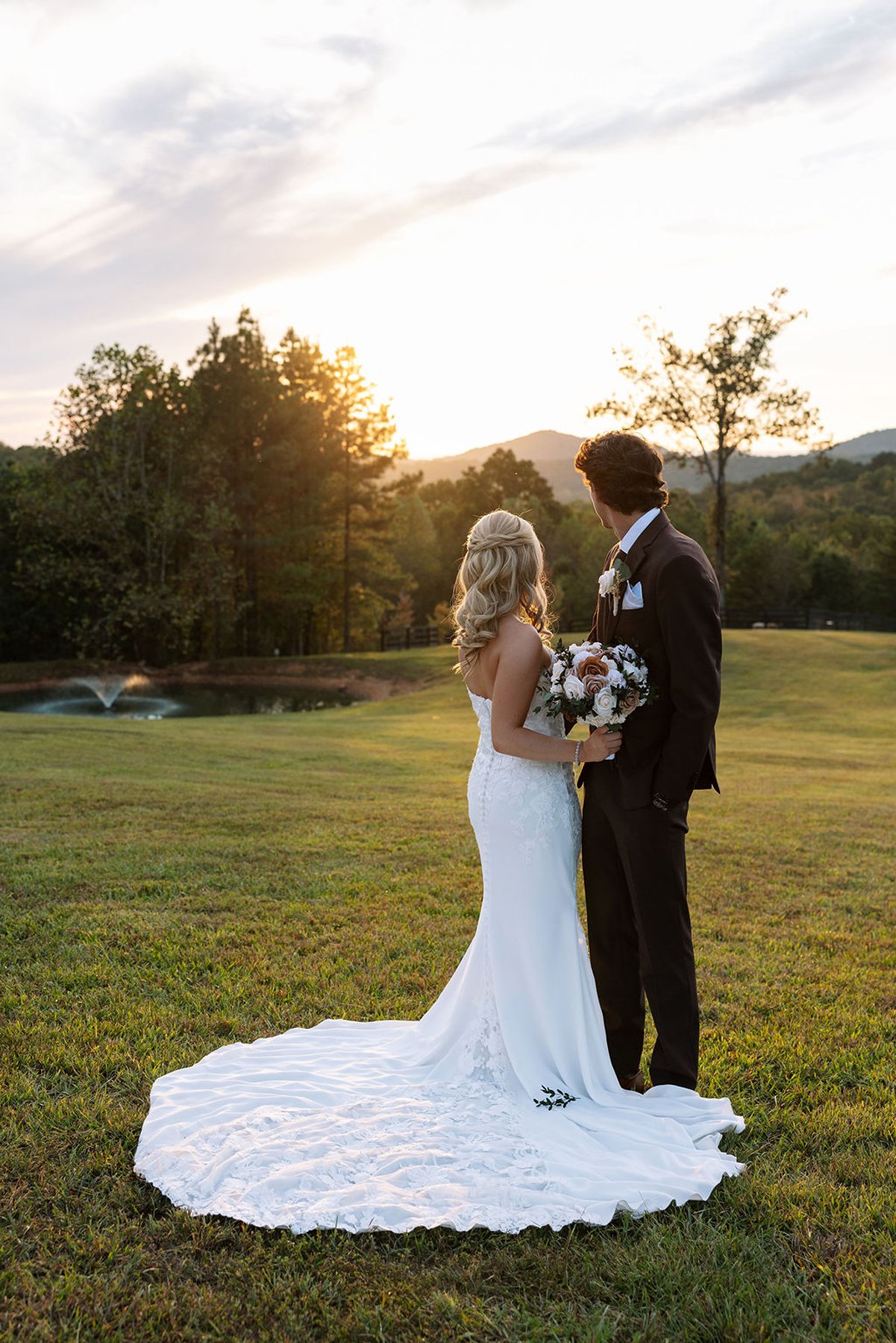 Bride and groom holding each other, framed by rolling hills and evening light