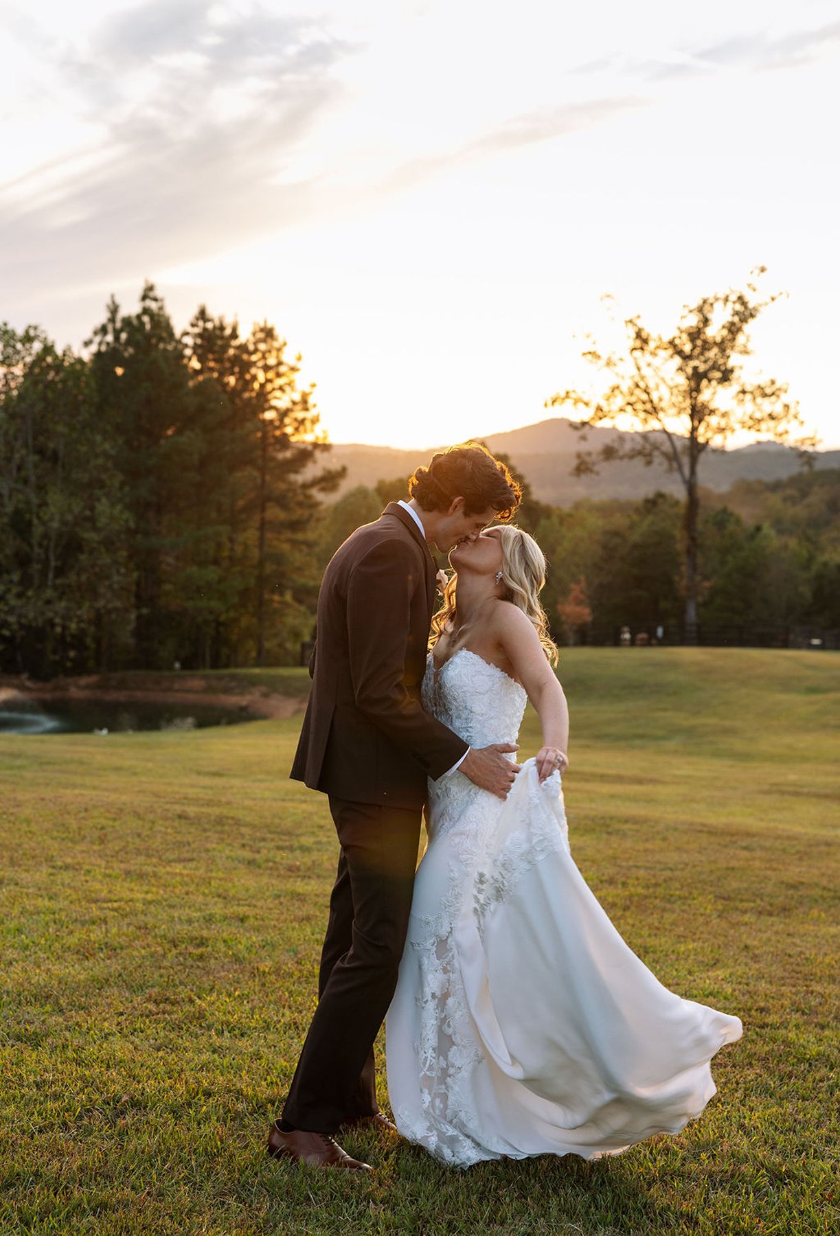 Groom kissing bride during sunset, warm light across Tennessee landscape