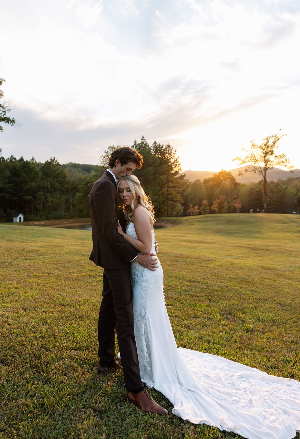Bride and groom standing together at sunset with rolling hills behind them