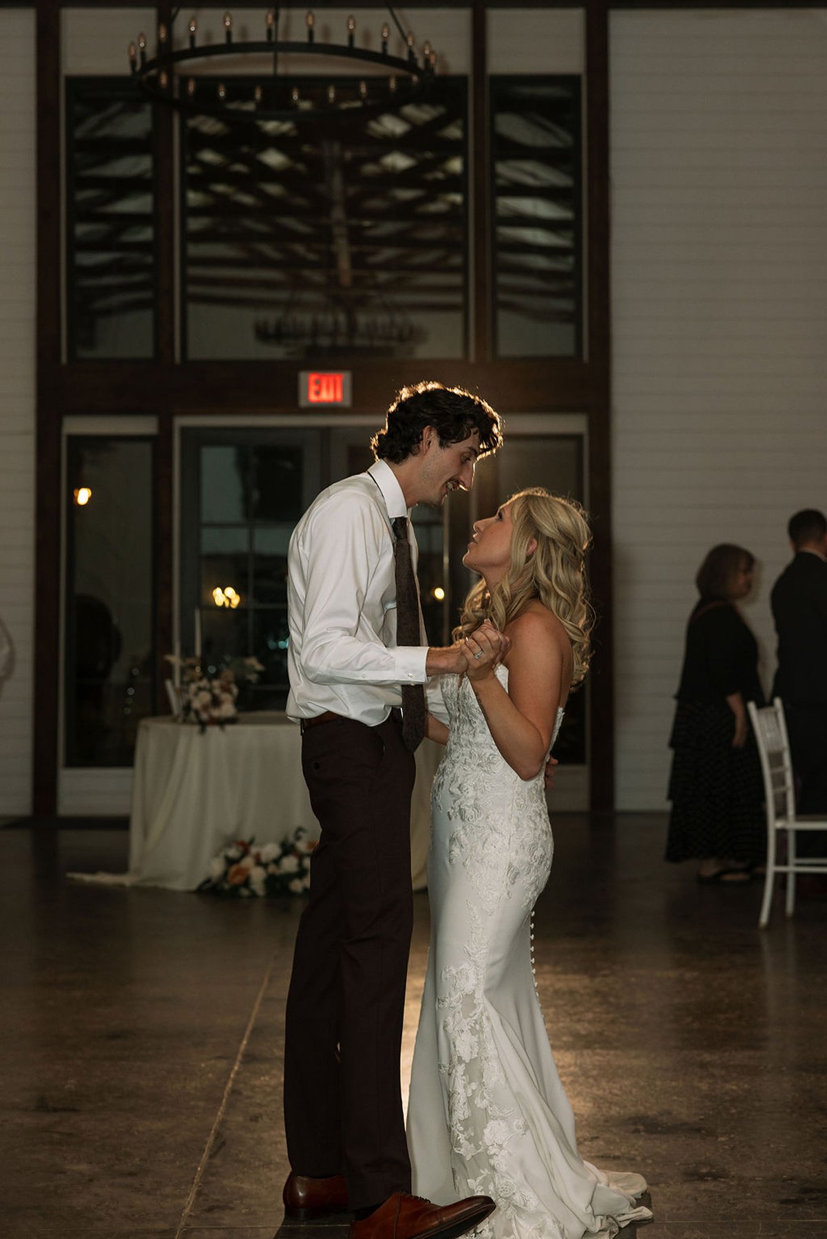 Bride and groom sharing first dance in softly lit reception space