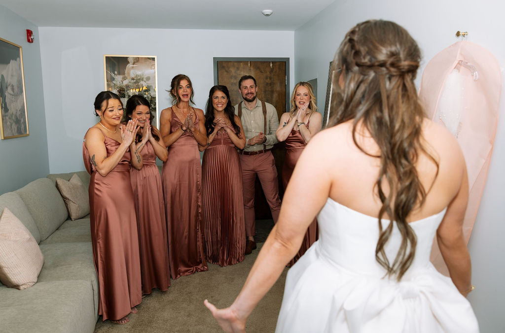 Bridesmaids reacting to the bride in her dress during getting ready, joyful and emotional moment