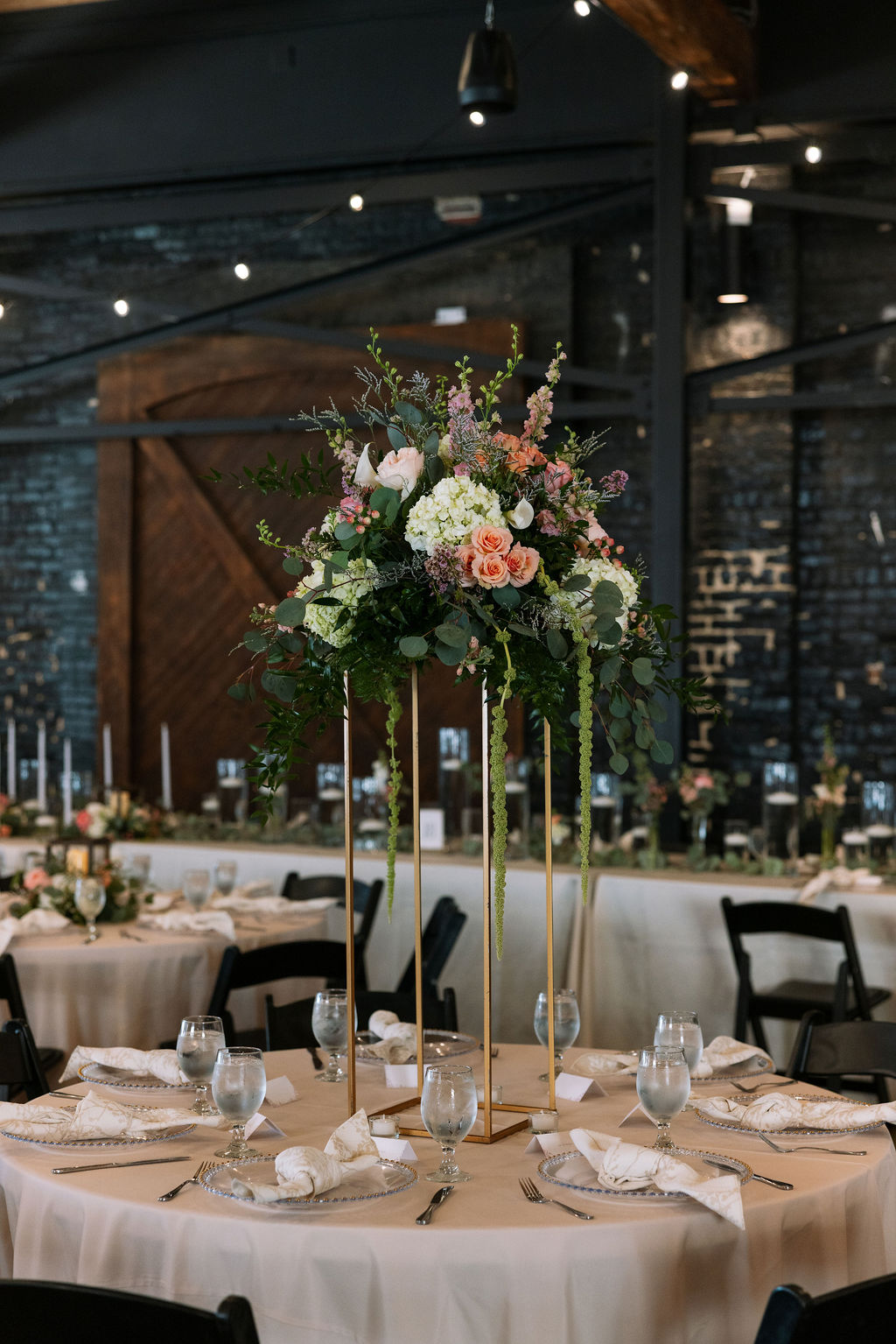 Tall floral centerpiece with greenery and blush flowers on reception table at Jackson Terminal Knoxville