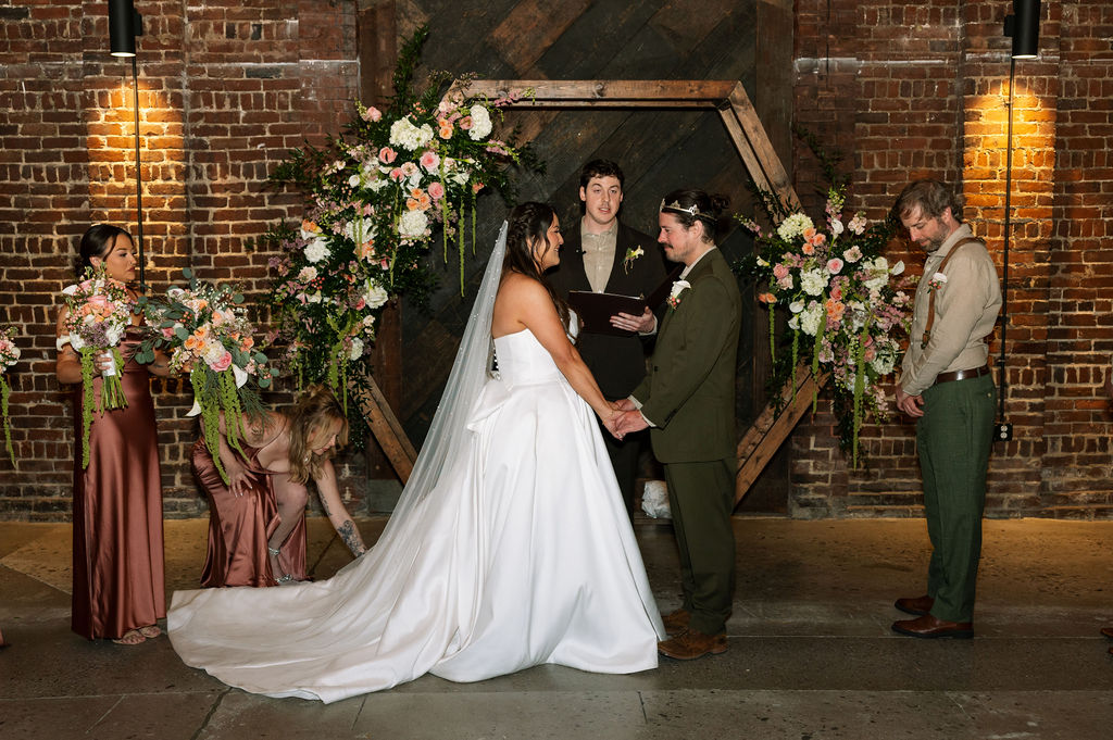 Wedding ceremony setup at Jackson Terminal Knoxville with exposed brick, floral arch, and couple at the altar
