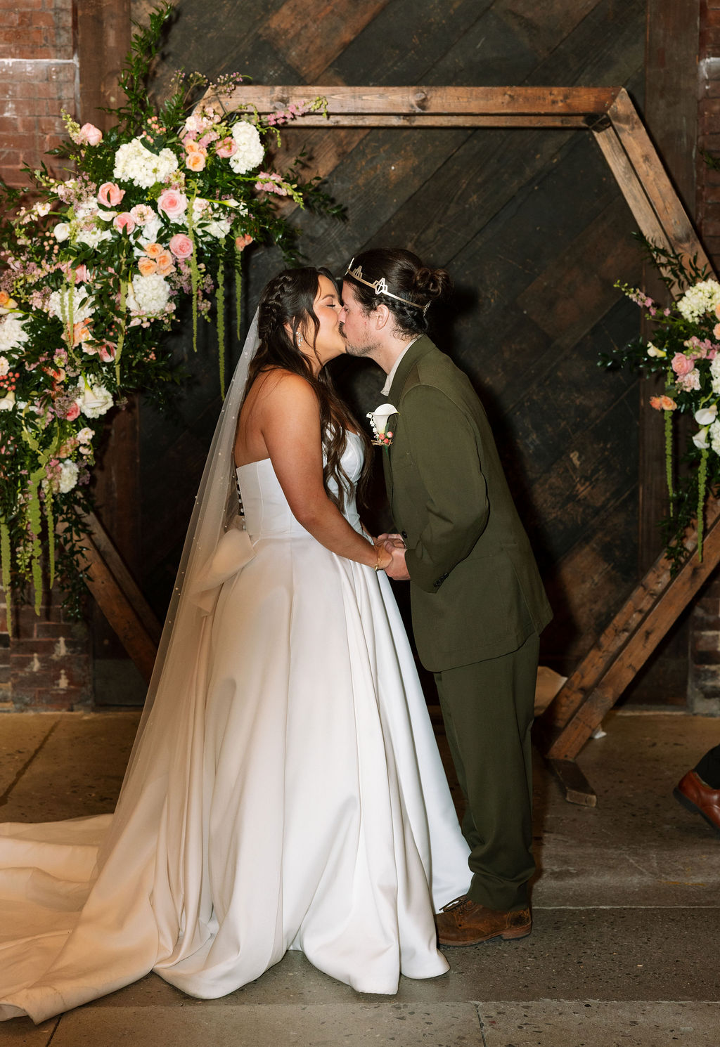 Bride and groom kissing in front of floral ceremony arch at Jackson Terminal Knoxville