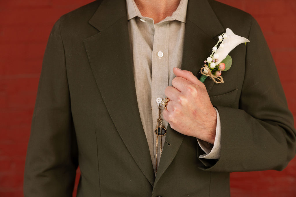 Close-up of groom’s boutonniere and suit details with floral accents and layered textures