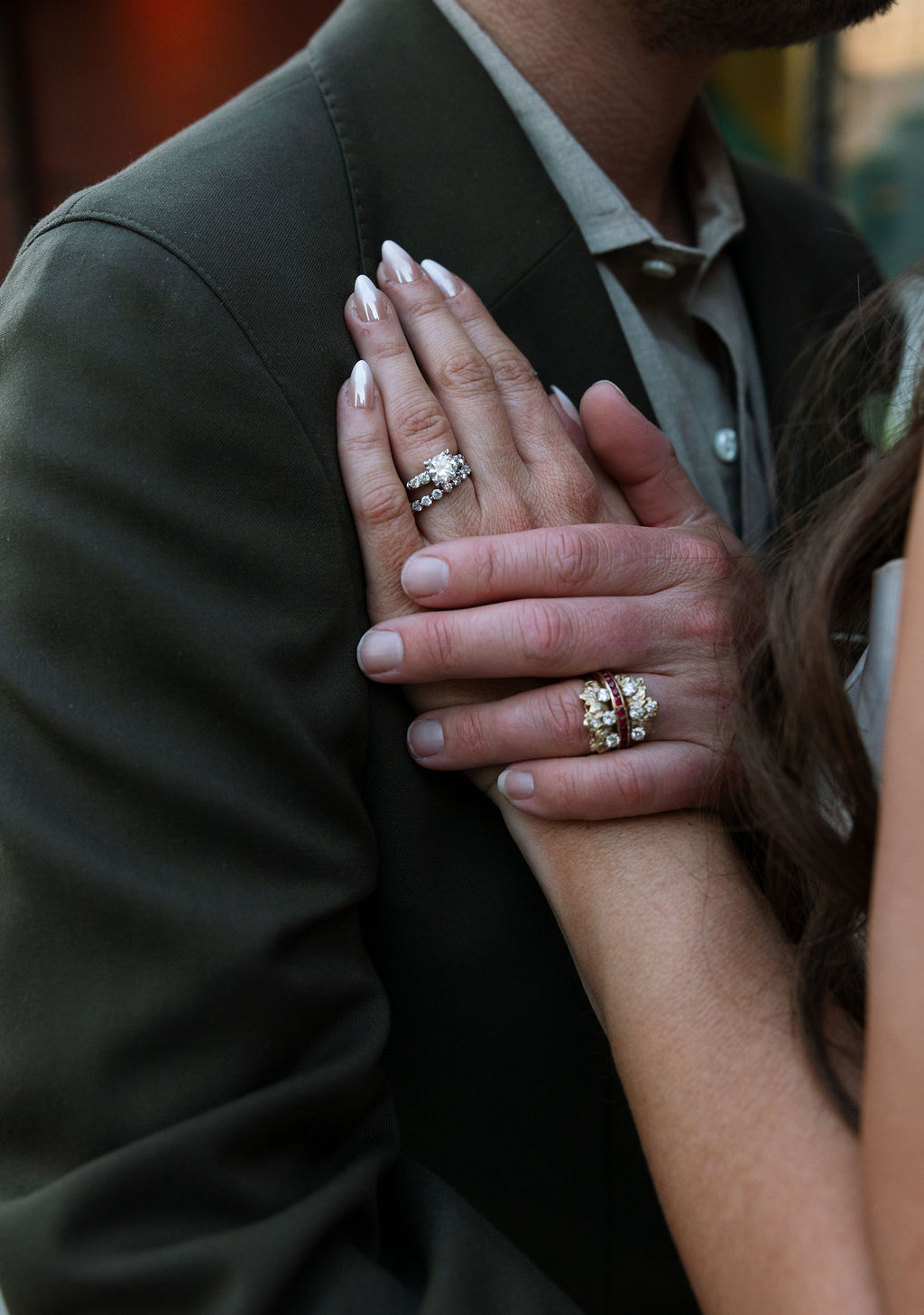 Close-up of wedding rings on bride and groom hands with green suit detail