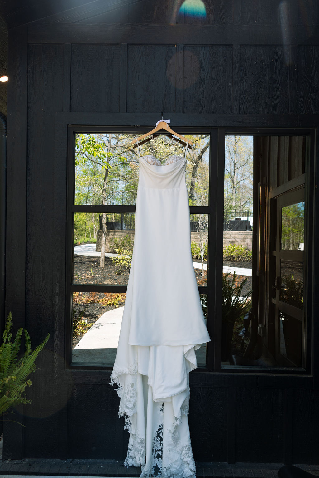 Wedding dress hanging in front of window with natural light, simple and clean bridal detail at a nichols heir wedding
