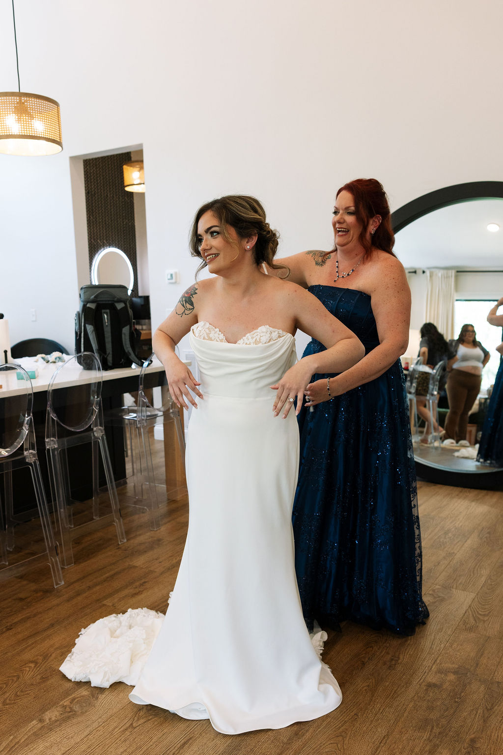 Bride getting ready with bridesmaid helping into dress, candid moment inside bridal suite at a nichols heir wedding