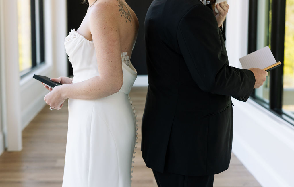 Close-up of bride and groom reading vows back to back, emotional pre-ceremony moment