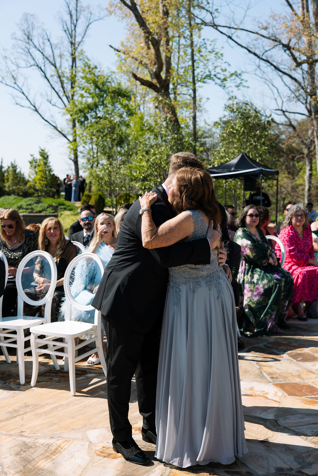 Emotional hug between groom and family member during ceremony processional
