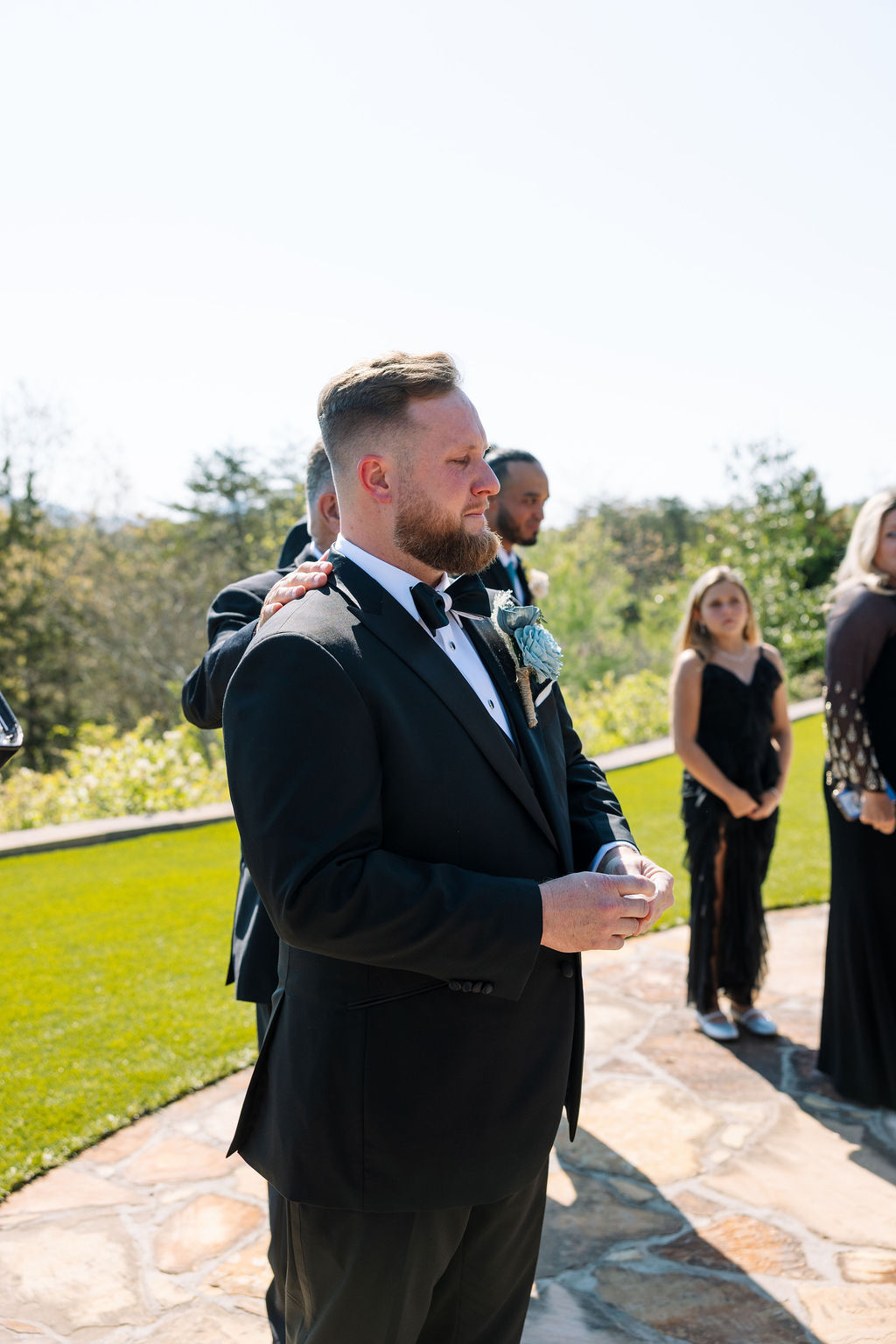 Groom standing at ceremony with groomsmen, waiting as guests look on at a nichols heir wedding