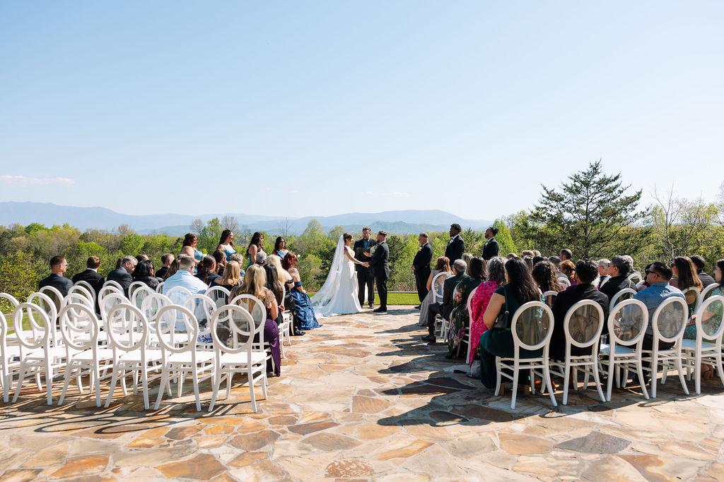 Wide view of outdoor ceremony with guests seated and mountain landscape in the distance