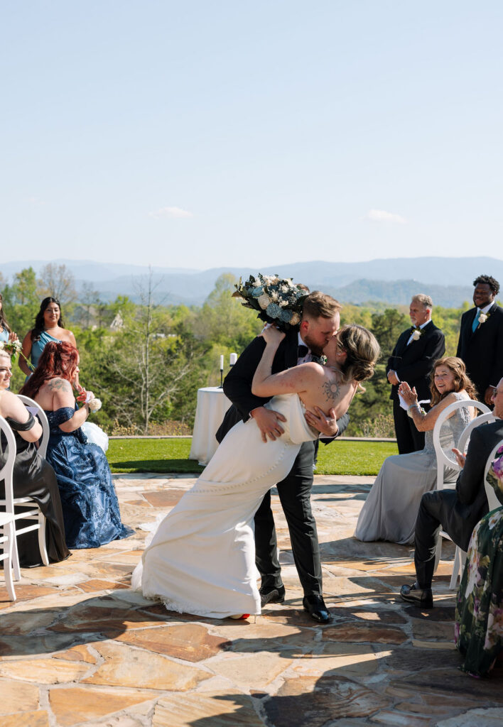 Bride and groom celebrating with a dip kiss during ceremony recessional at a nichols heir wedding