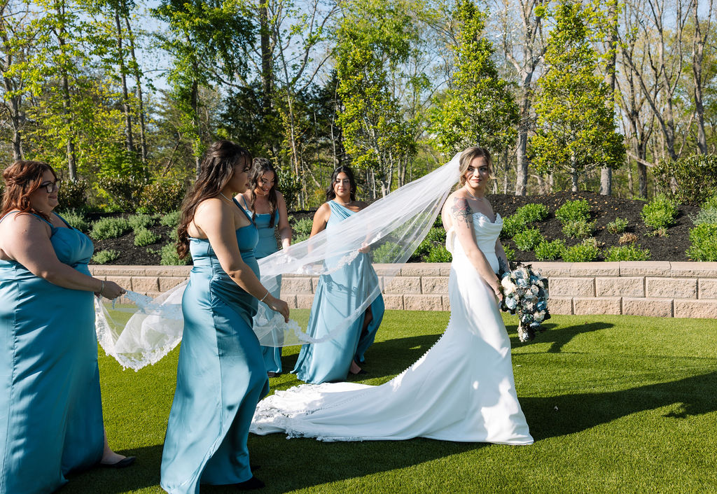 Bridesmaids adjusting bride’s veil and dress before ceremony on lawn at a nichols heir wedding