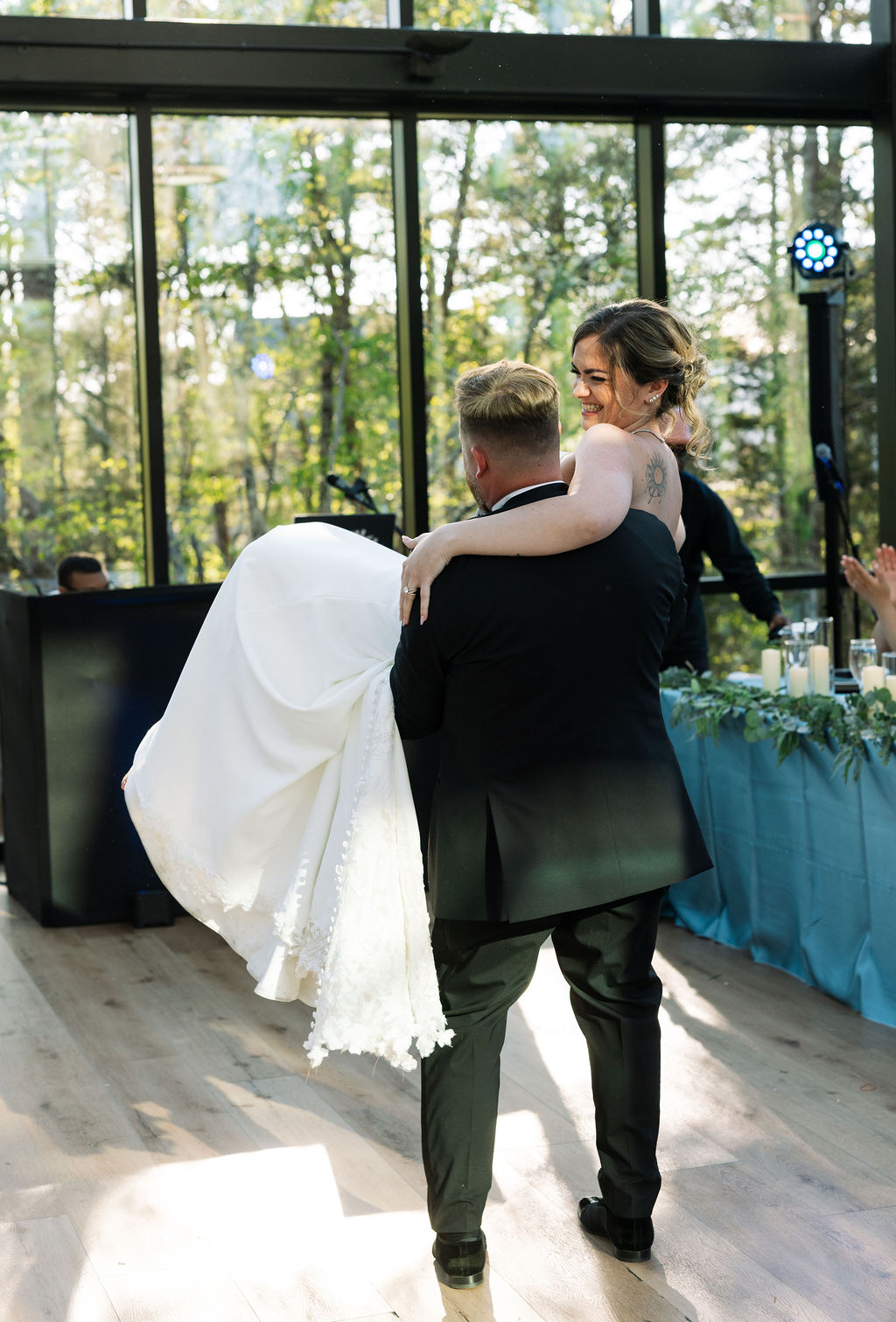 Groom carrying bride into reception space, joyful entrance moment at a nichols heir wedding