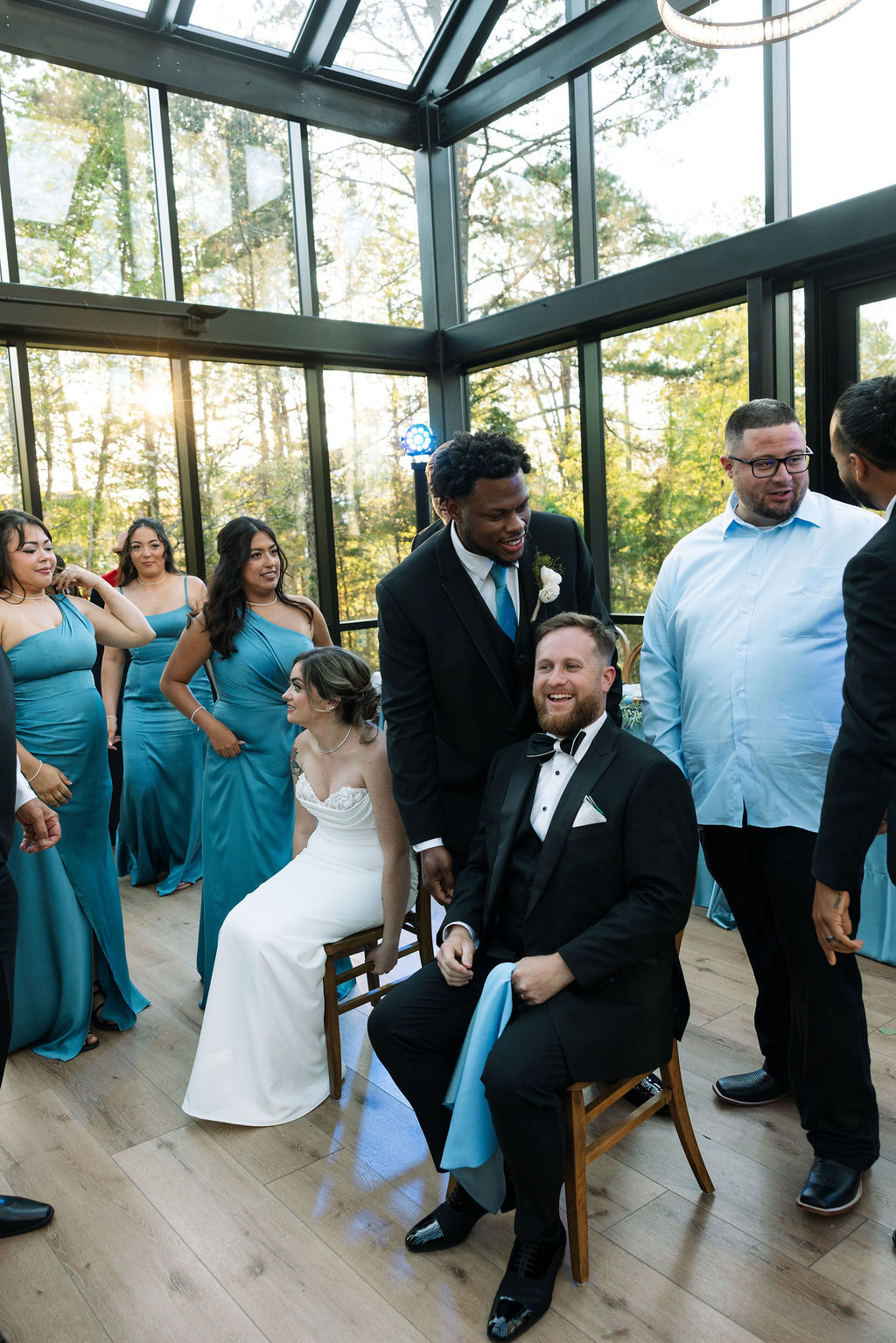 Wedding party playing shoe game inside glass reception space with natural light at a nichols heir wedding