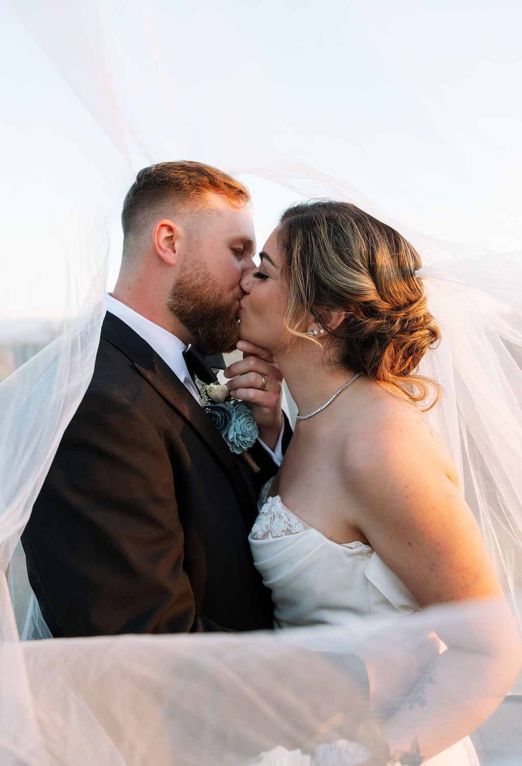 Close-up of bride and groom kissing under veil with soft sunset light at a nichols heir wedding
