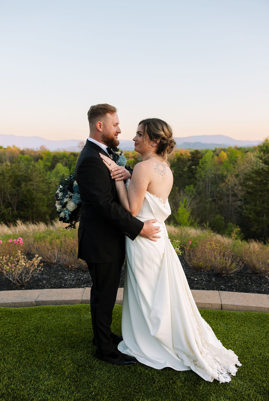 Bride and groom embracing during golden hour portraits with scenic overlook backdrop
