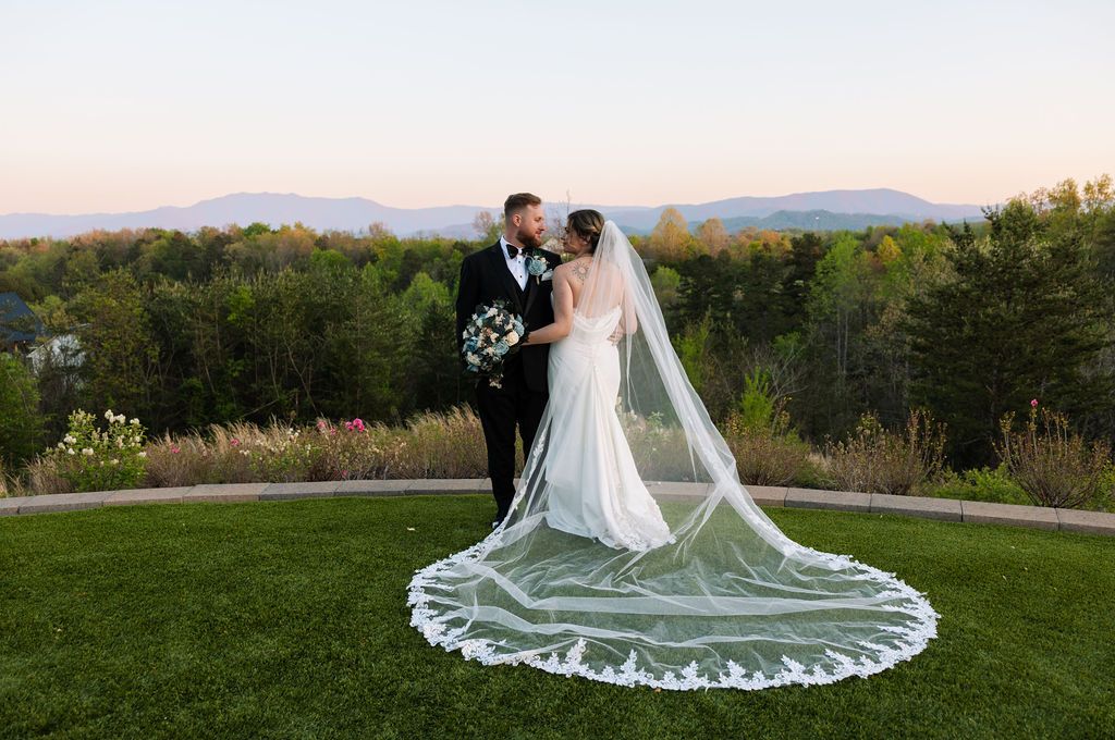 Bride and groom embracing with sweeping veil and mountain views during sunset portraits at a nichols heir wedding