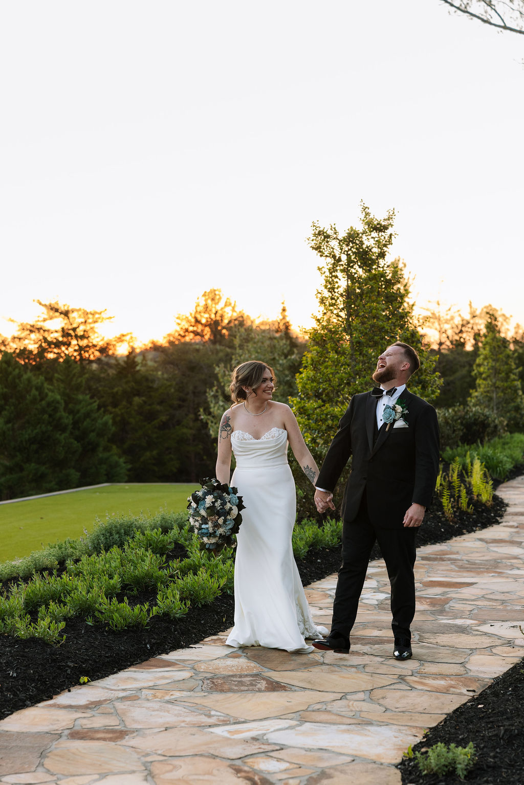 Bride and groom walking hand in hand at sunset along stone path during a nichols heir wedding