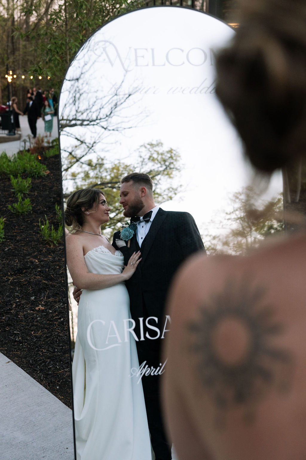 Bride and groom reflected in welcome sign mirror during cocktail hour at a nichols heir wedding