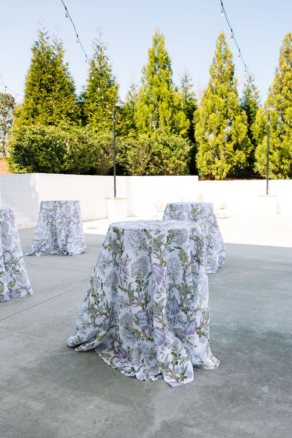 Cocktail tables set with floral linens on an outdoor patio at Howe Farms wedding venue