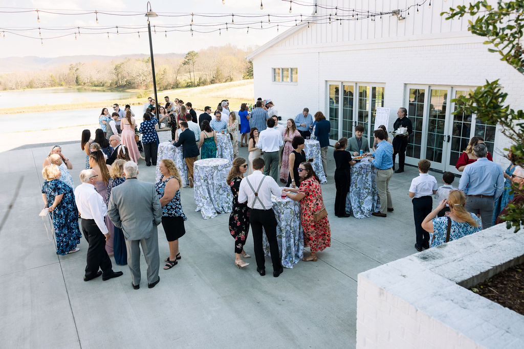 Guests mingling outside during cocktail hour on the patio at Howe Farms wedding venue