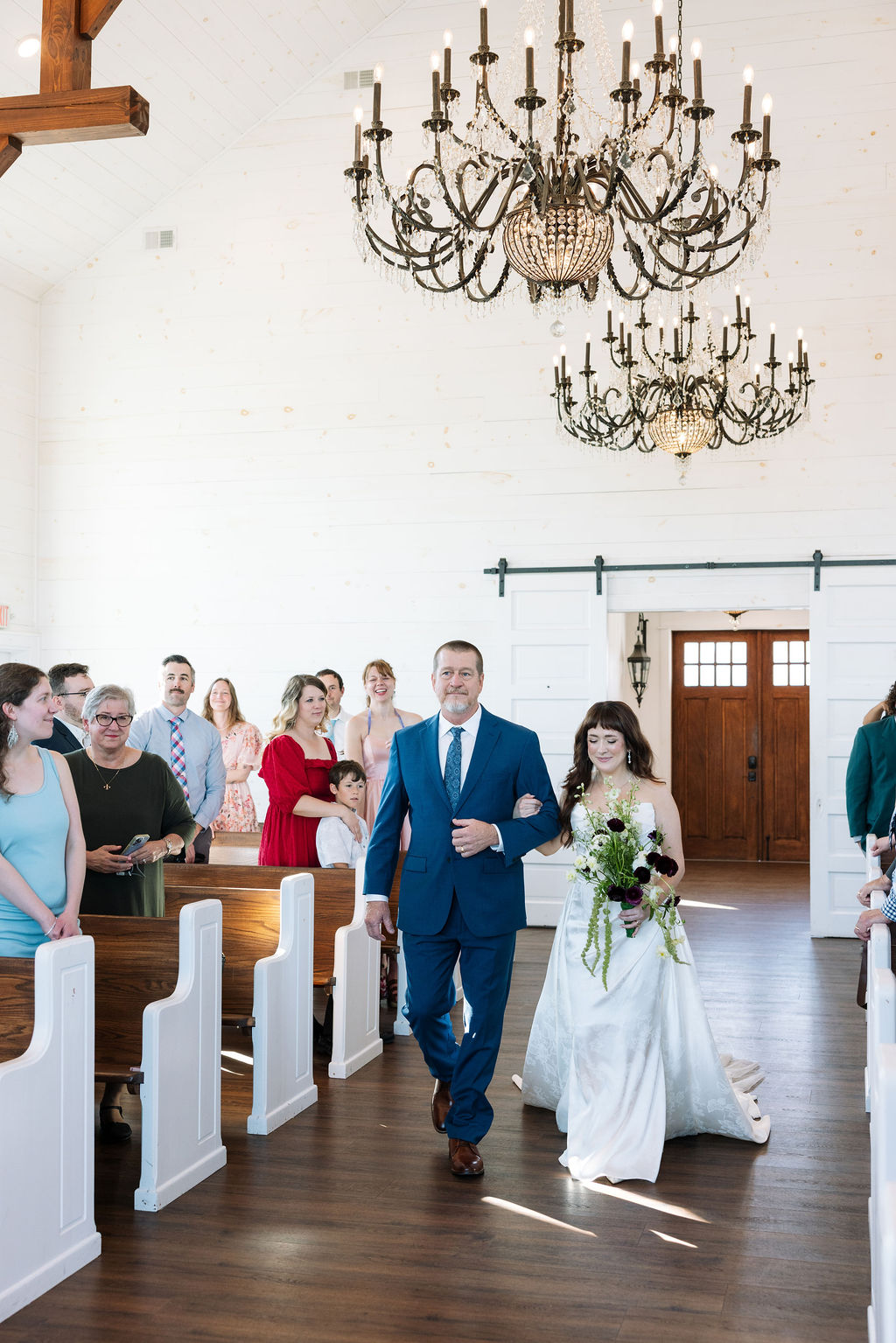 Bride walking down the aisle with her father inside the chapel at Howe Farms wedding venue