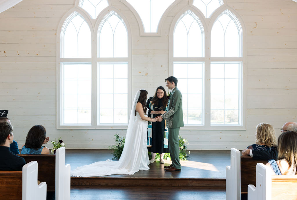 Couple exchanging vows during their ceremony inside the chapel at Howe Farms wedding venue