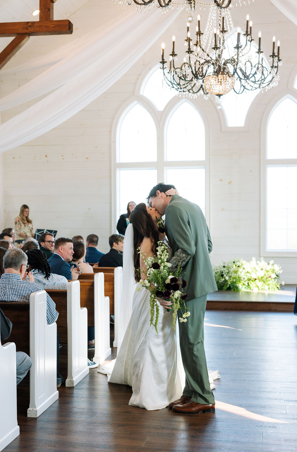 Bride and groom kissing at the altar inside a light-filled chapel