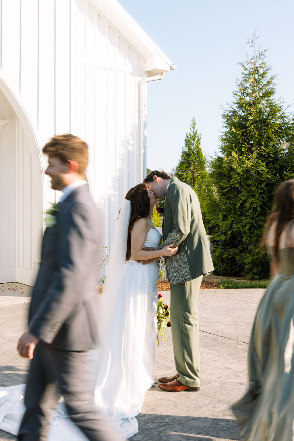 Bride and groom share a quiet moment beside a white church following their wedding ceremony.