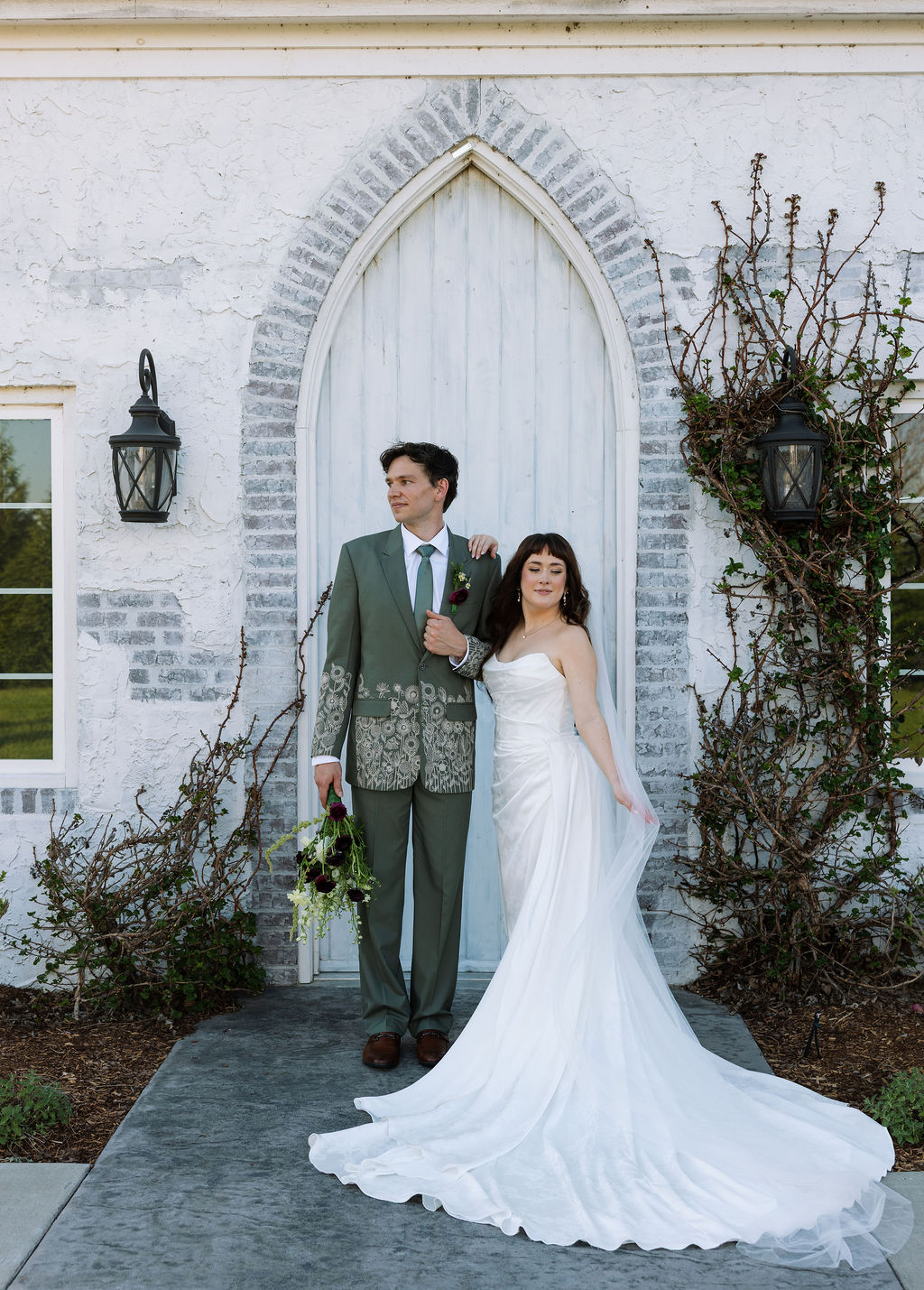 Couple standing together in front of an arched doorway with ivy at Howe Farms wedding venue
