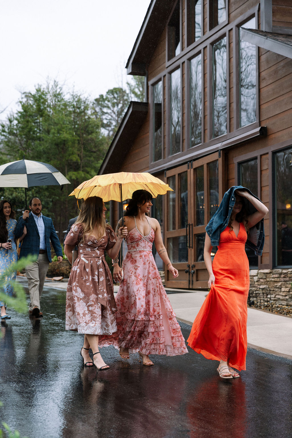 Guests walking in the rain with umbrellas outside the reception space at The Magnolia Wedding Venue
