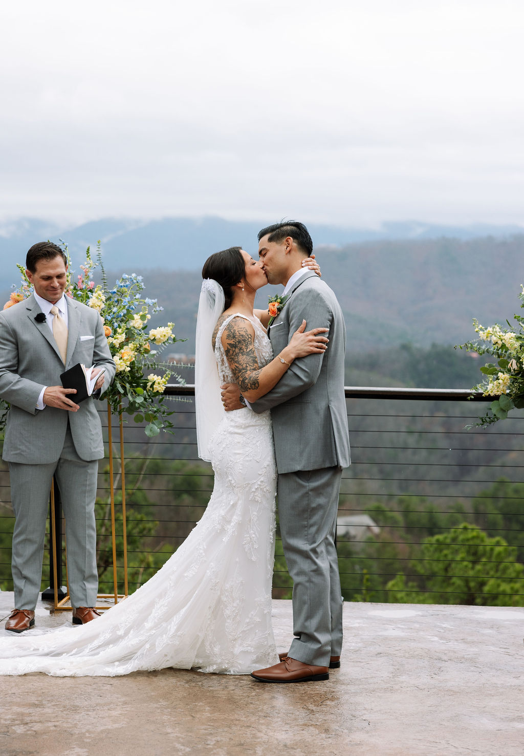 Bride and groom share their first kiss at The Magnolia Wedding Venue during an outdoor mountain ceremony
