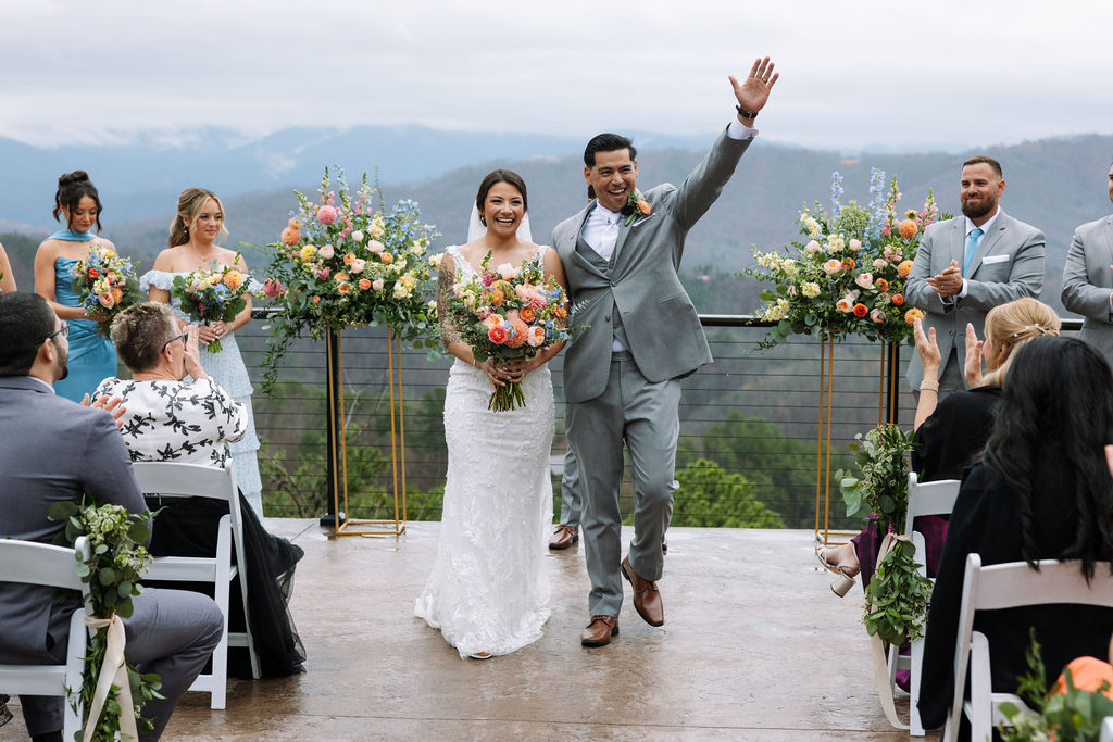 Newlyweds walk back down the aisle smiling as guests applaud at The Magnolia Wedding Venue
