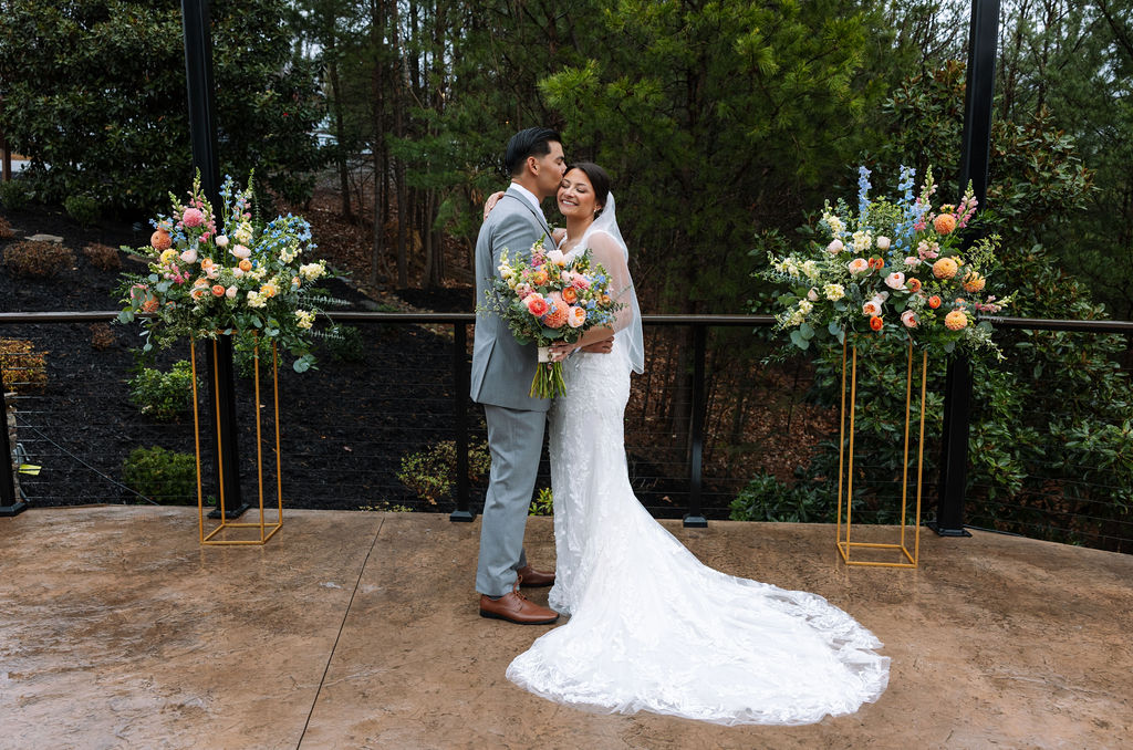 Bride and groom embrace in front of ceremony florals at The Magnolia Wedding Venue after the ceremony
