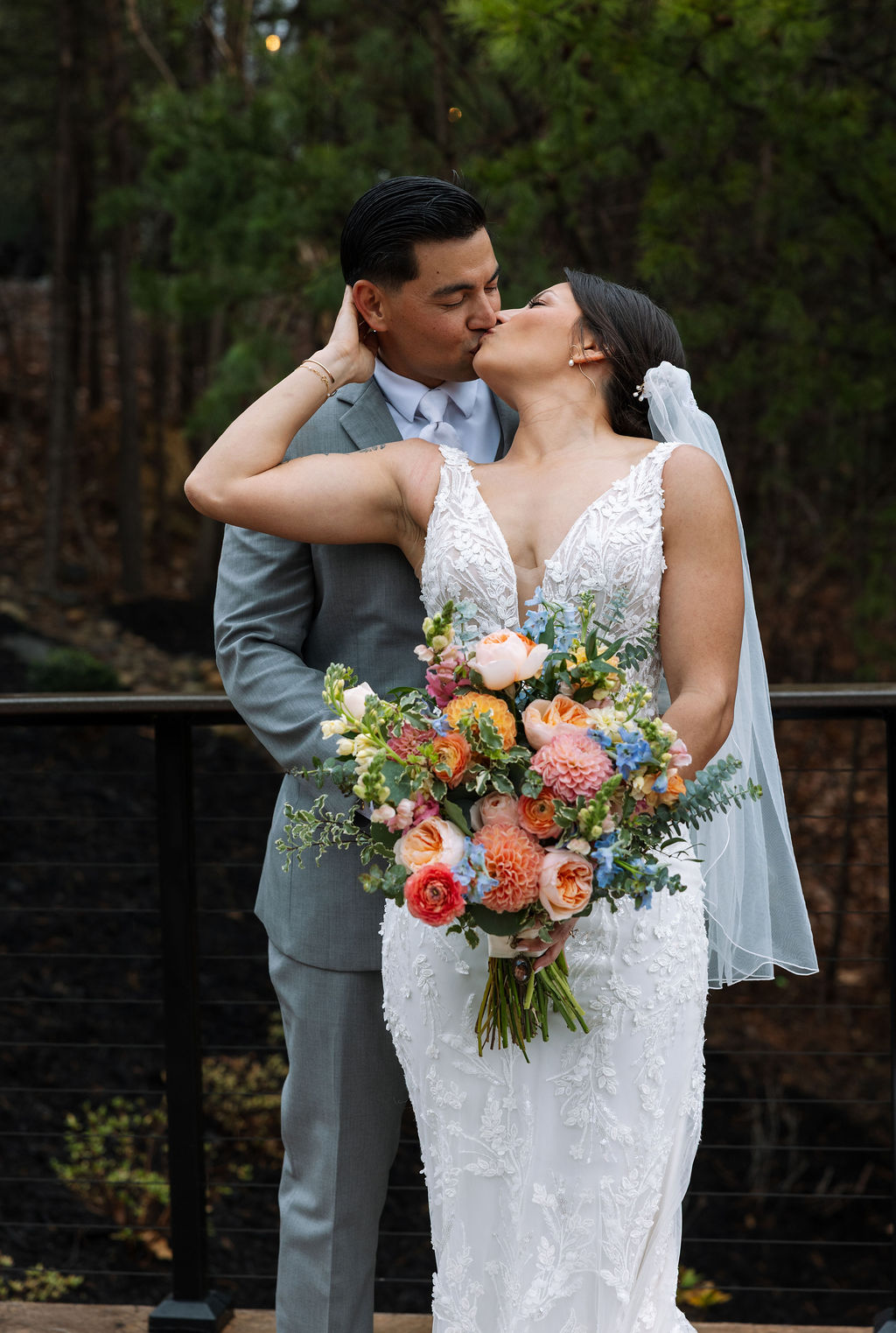 Bride and groom sharing a kiss with colorful bouquet on the patio at The Magnolia Wedding Venue
