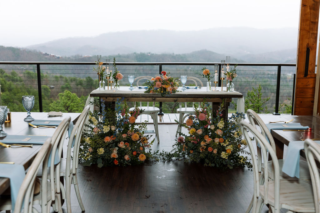 Reception sweetheart table with florals and mountain views inside The Magnolia Wedding Venue
