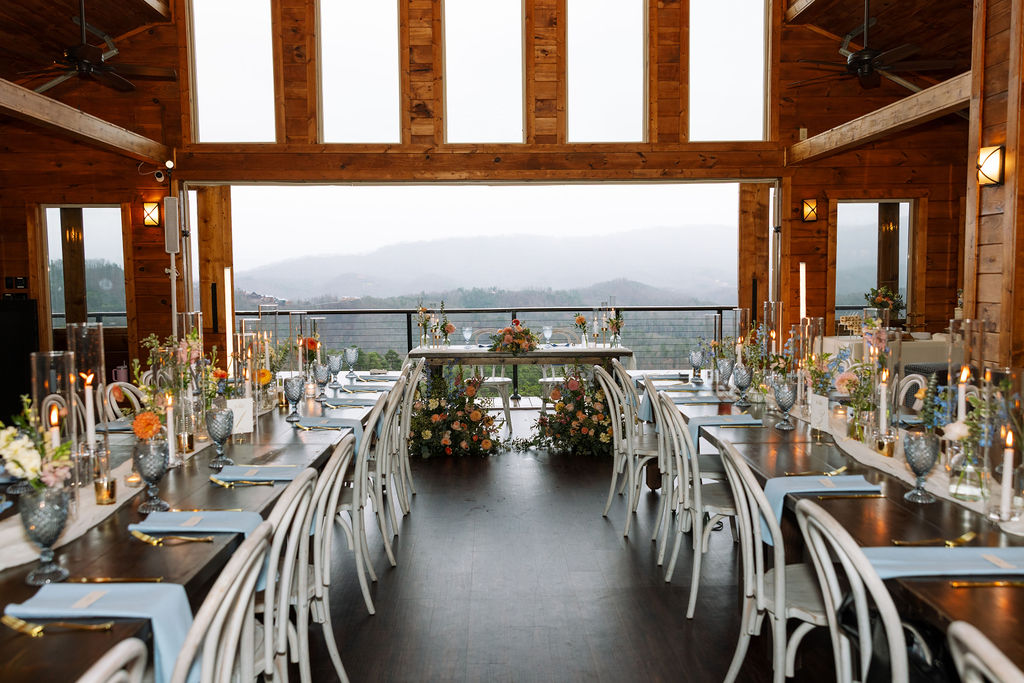 Reception table design inside The Magnolia Wedding Venue with long wooden tables, candles, florals, and mountain views
