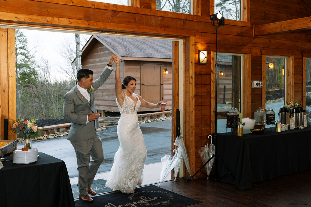 Bride and groom entering their reception space together, smiling and holding hands at The Magnolia Wedding Venue

