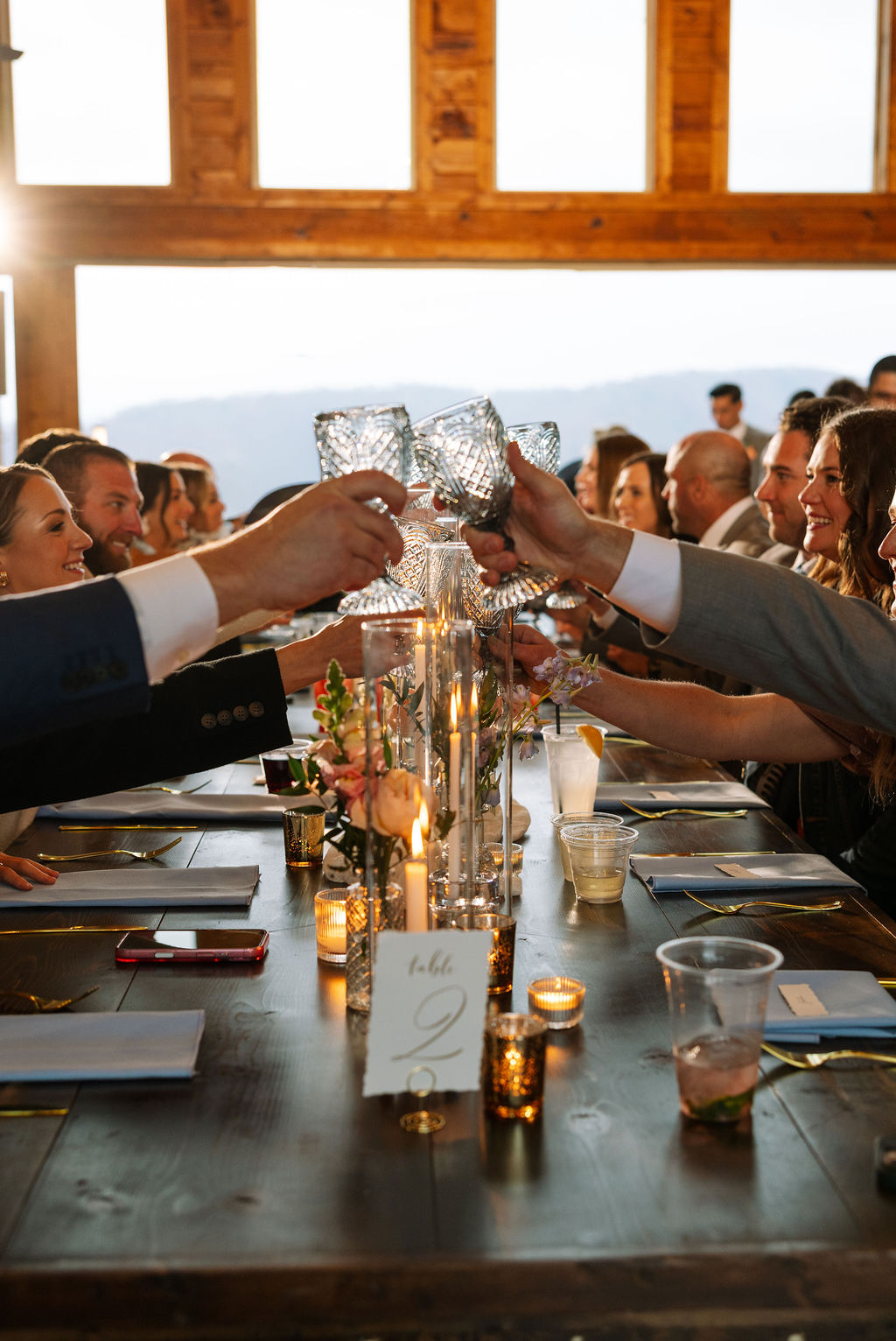 Guests raising glasses for a toast at a candlelit reception table at The Magnolia Wedding Venue
