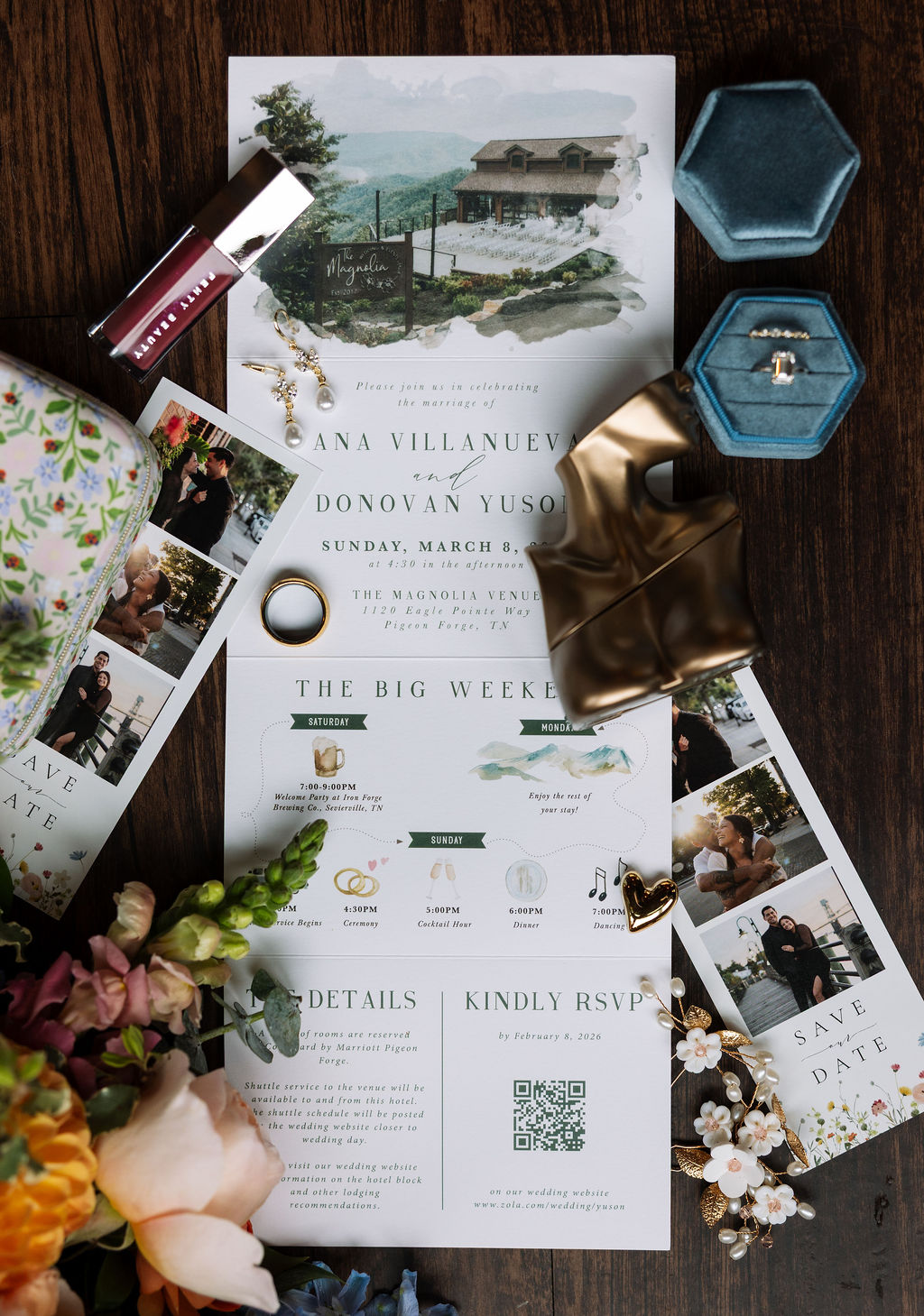 Flat lay of wedding invitation suite with printed details, rings, heirloom jewelry, and soft floral accents
