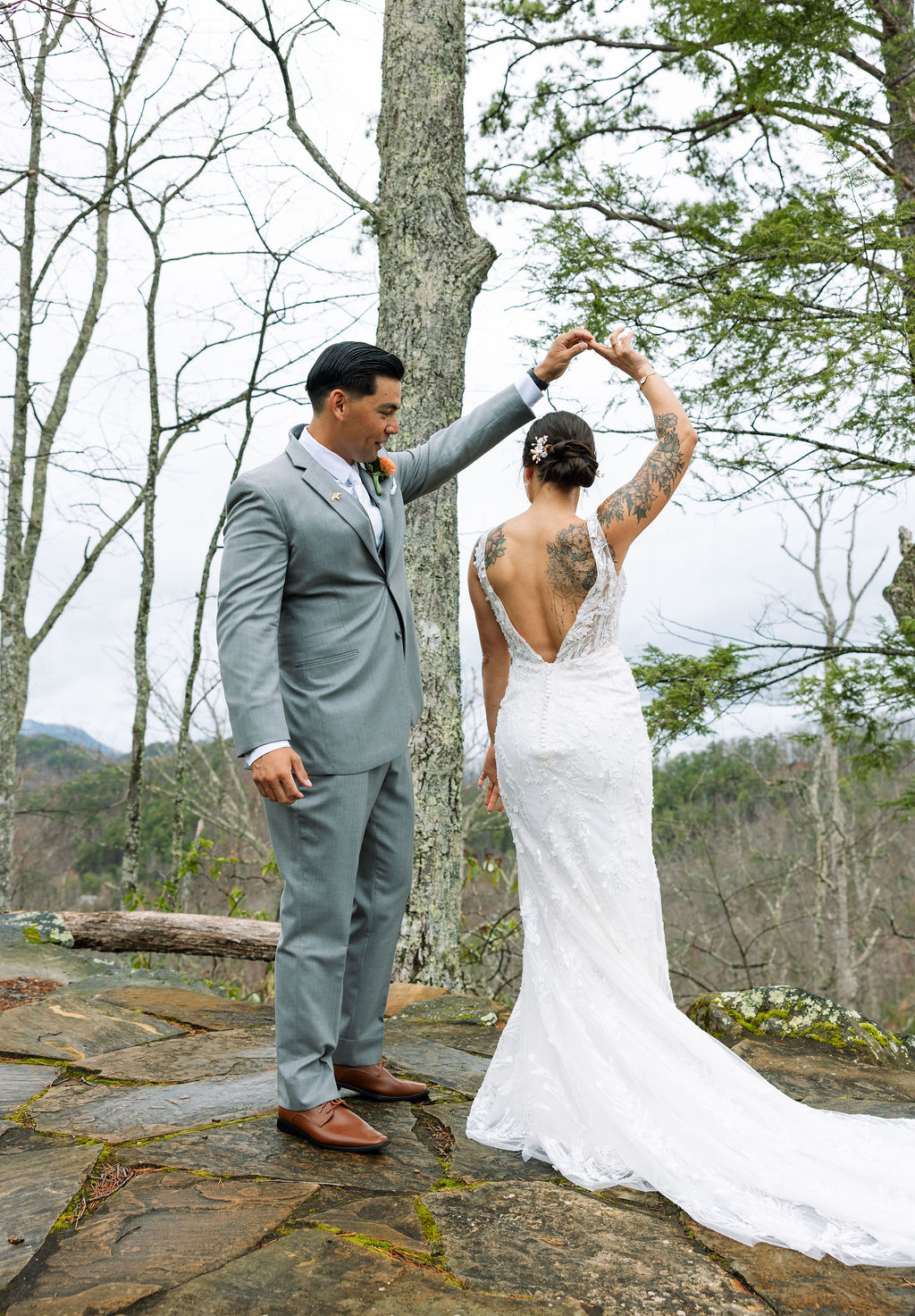 Groom twirls bride in her lace gown on a scenic overlook at The Magnolia Wedding Venue
