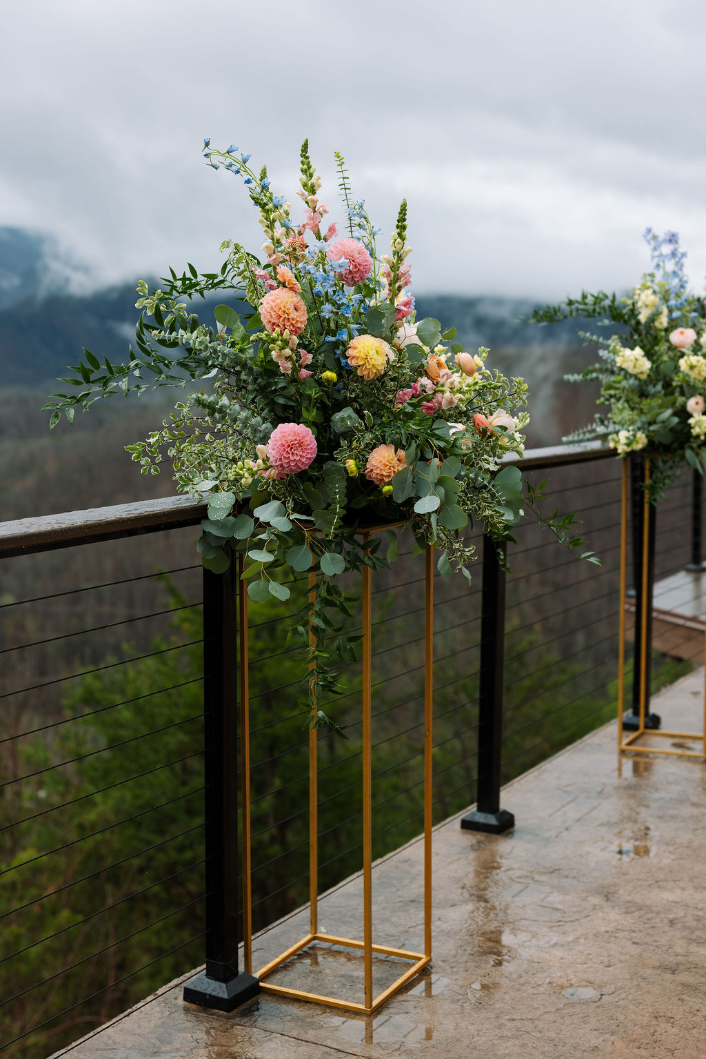 Ceremony floral arrangement in soft pastel tones on a gold stand overlooking the mountains at The Magnolia Wedding Venue
