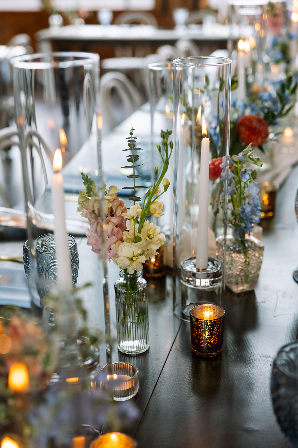 Reception table detail with textured glassware, candles, and soft florals during dinner service