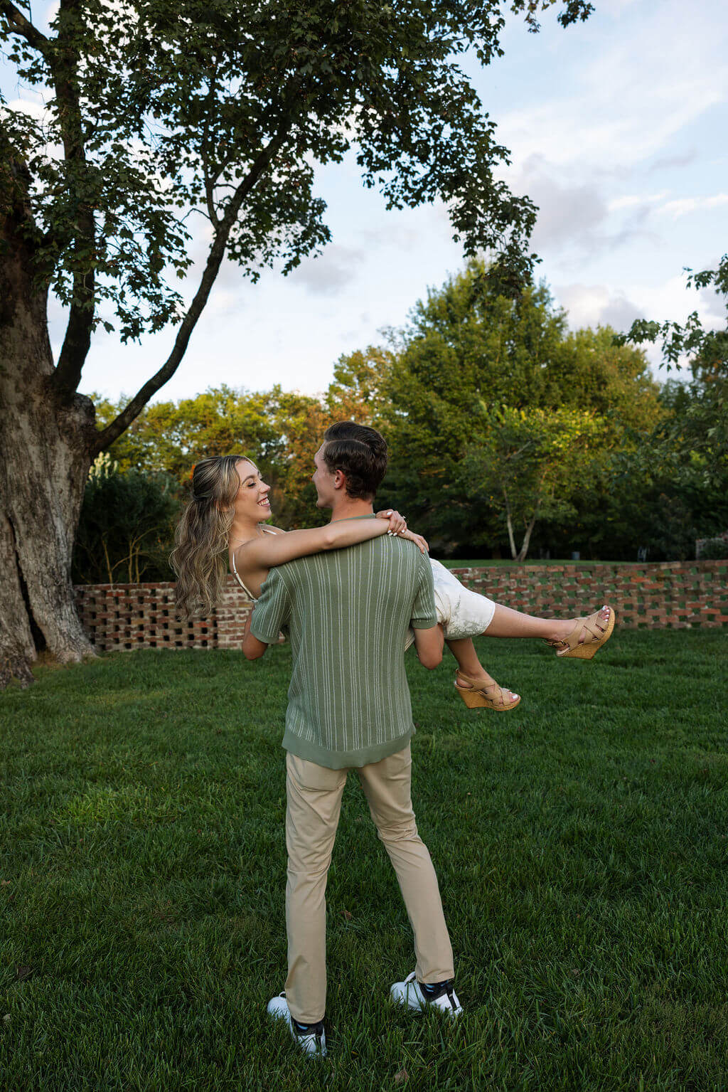 Playful engagement photos at Maple Grove Estate with groom carrying bride across the lawn