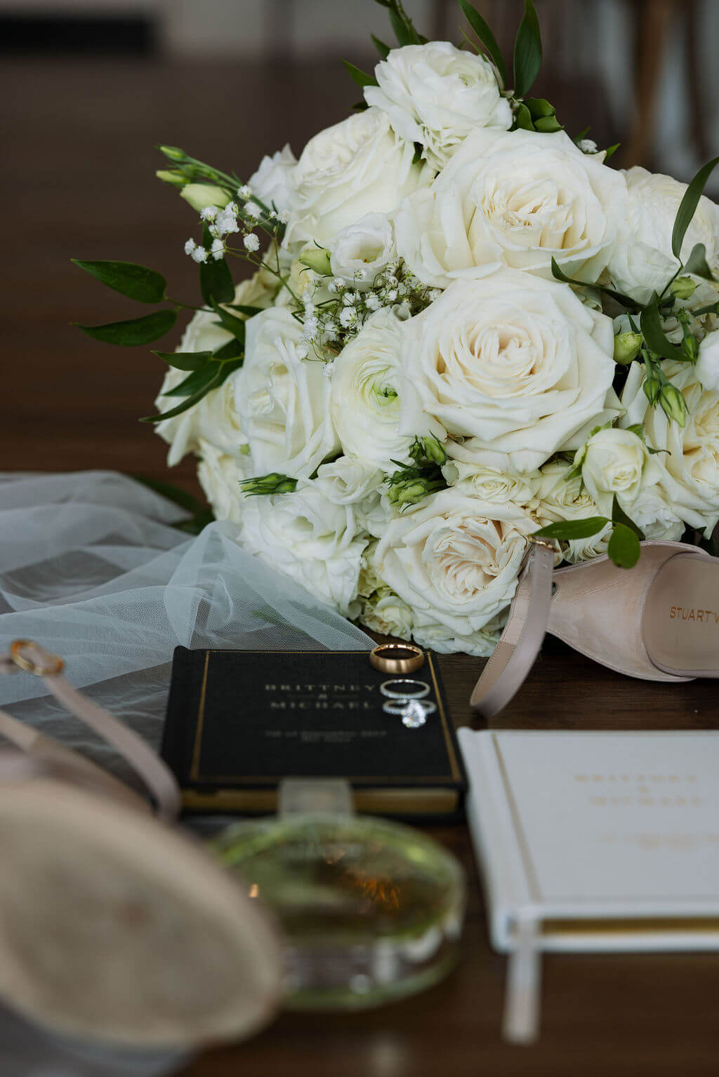 White wedding bouquet with invitation suite and wedding rings detail photo