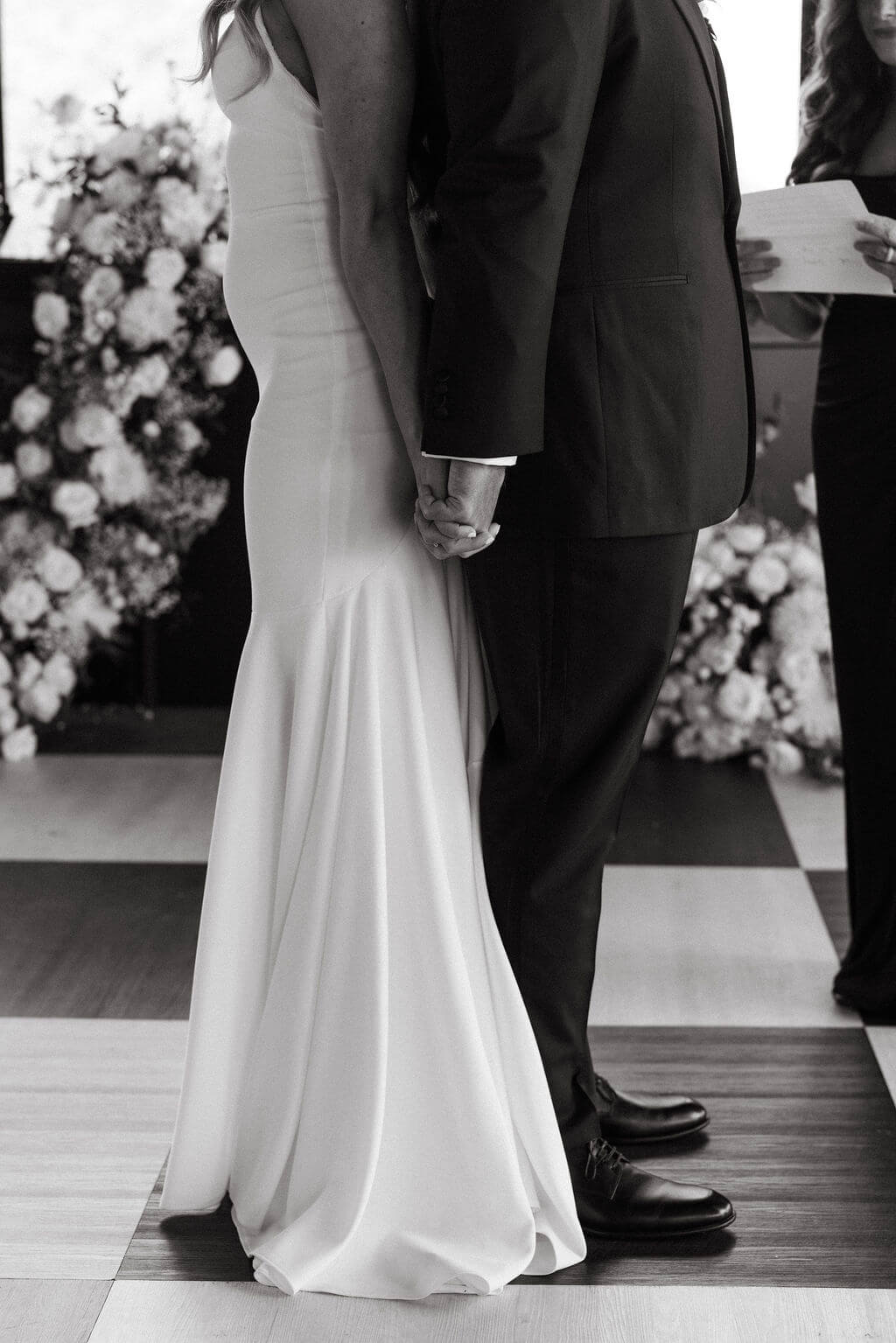 Black and white wedding ceremony detail photo of bride and groom holding hands
