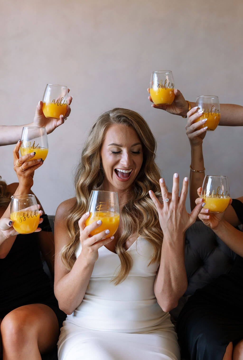 Bride celebrating engagement ring with bridesmaids during wedding morning preparations