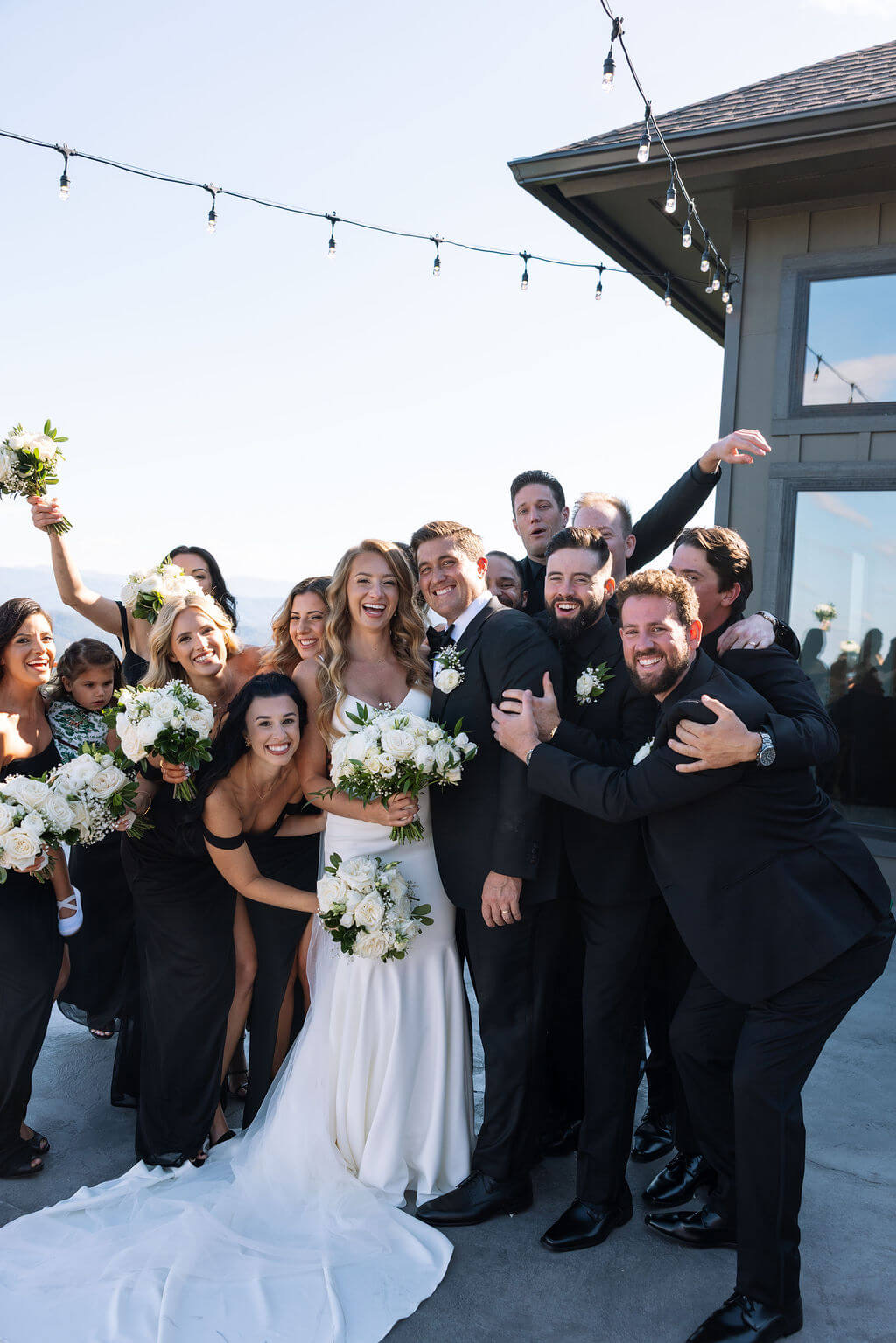 Bride and groom celebrating with their wedding party during a group portrait outside a mountain wedding venue.